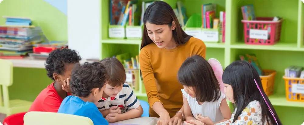 Preschool teacher with children around a table in class